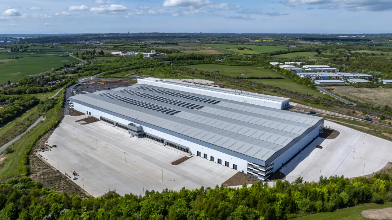 Aerial view of XDock 549, a large cross dock warehouse with rooftop solar panels, set in green countryside